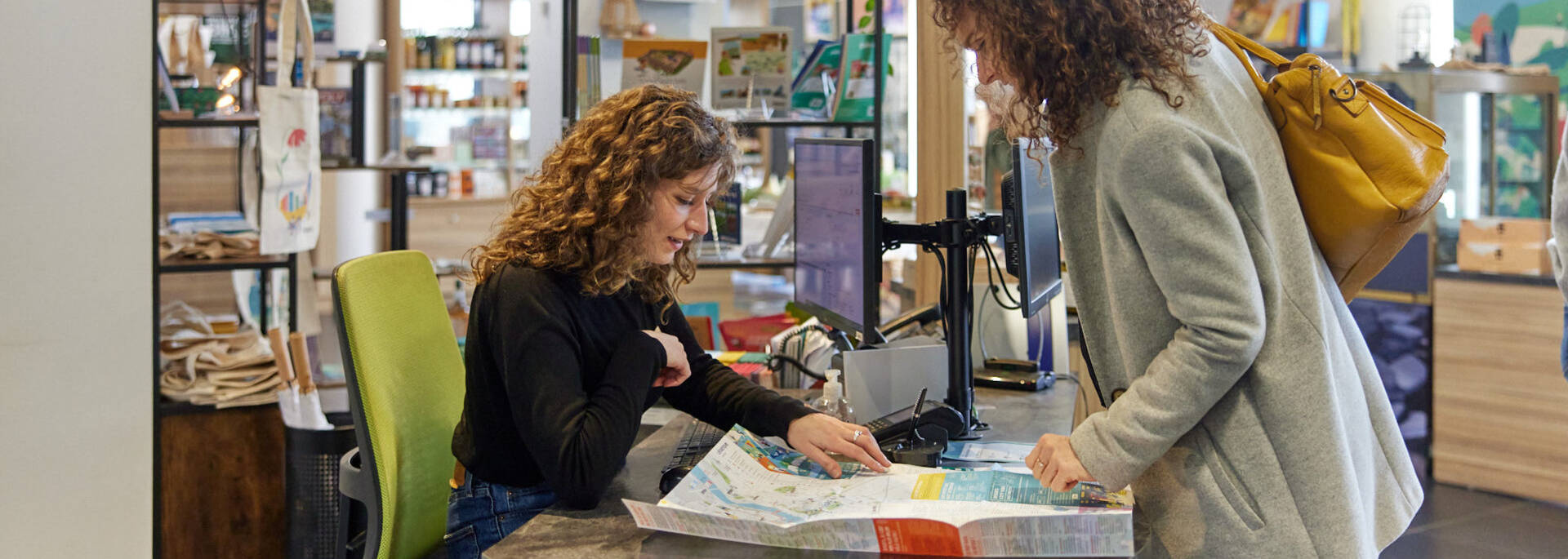 Advisor showing a map to a woman at the tourist office reception desk