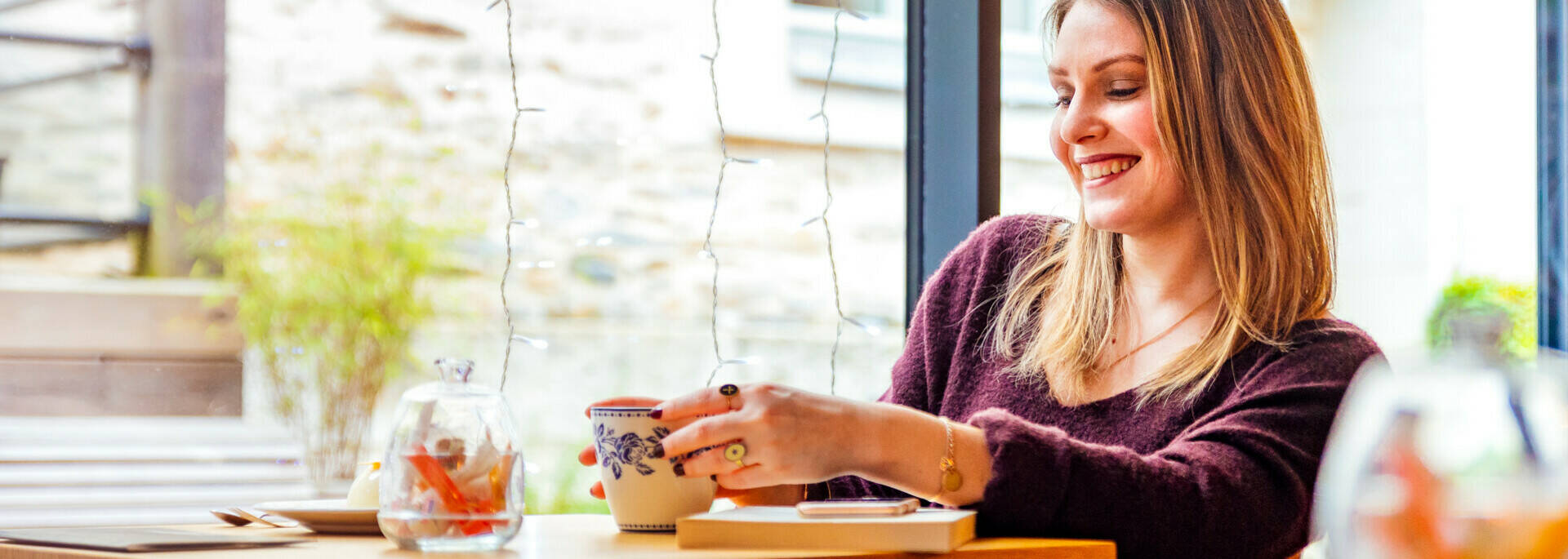Jeune femme souriante assise à une table dans un salon de thé