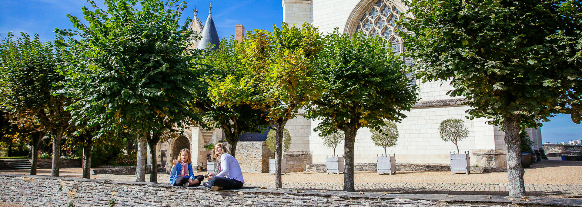 A mother and daughter sitting on a low wall in the castle grounds