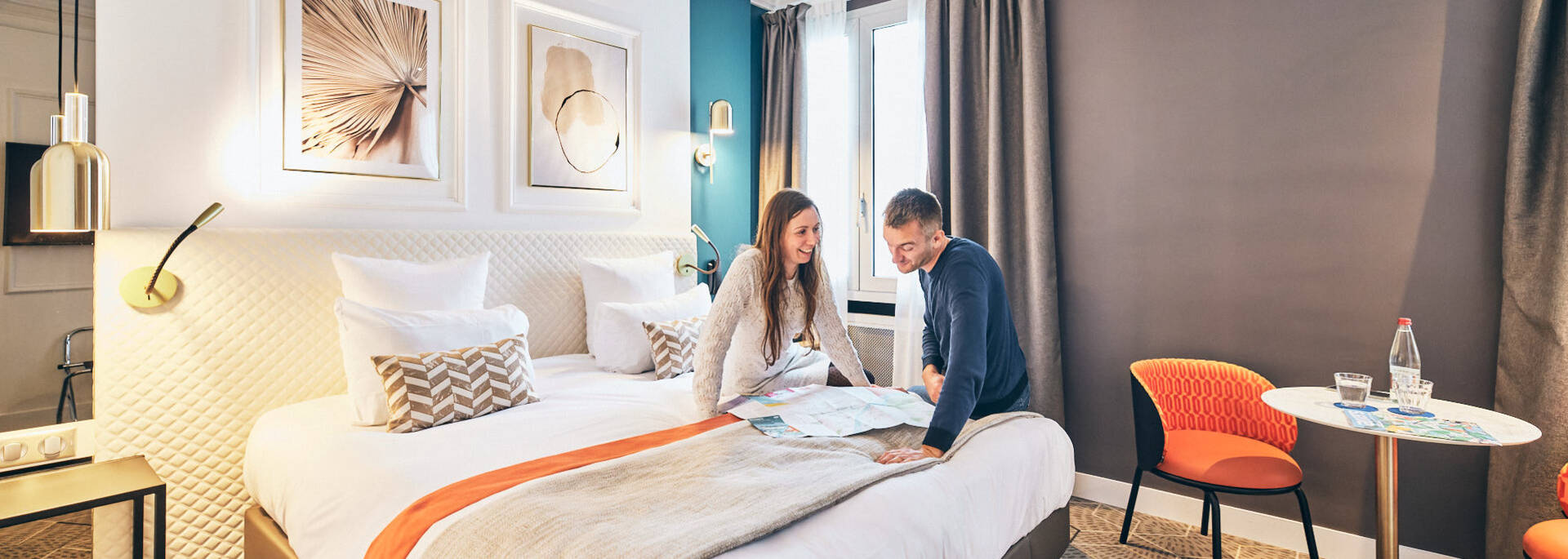 Couple discutant devant un plan assis sur le lit d'une chambre d'hôtel