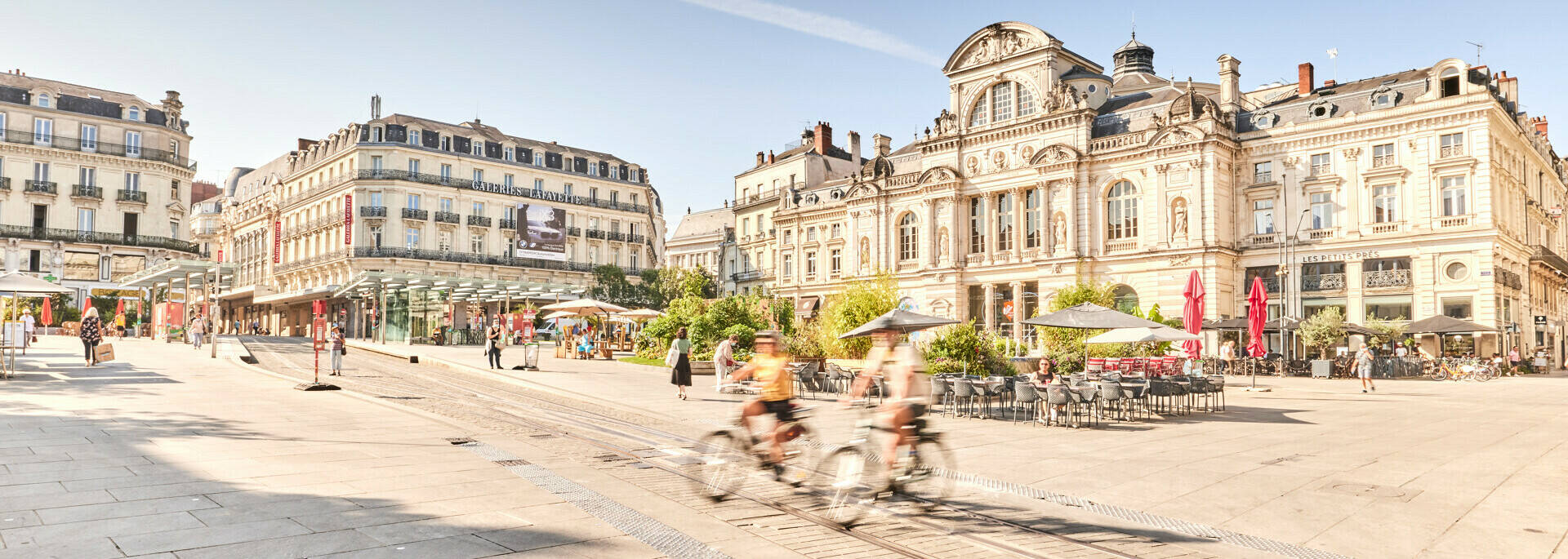 Two cyclists passing Place du Ralliement in front of the Grand Théâtre