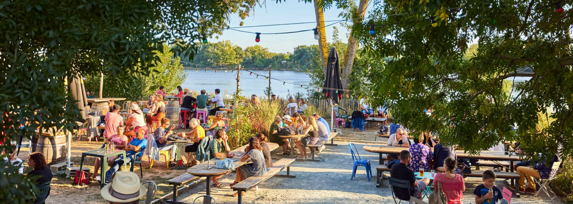 Summer atmosphere on the terrace of the guinguette of Port Thibault, many people enjoy the late evening in the sun facing the Loire