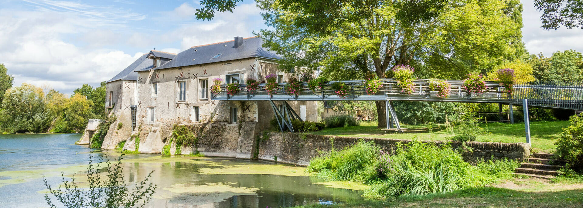 Wide shot of the mill on the banks of the Loir, spring sunshine, nice green vegetation 