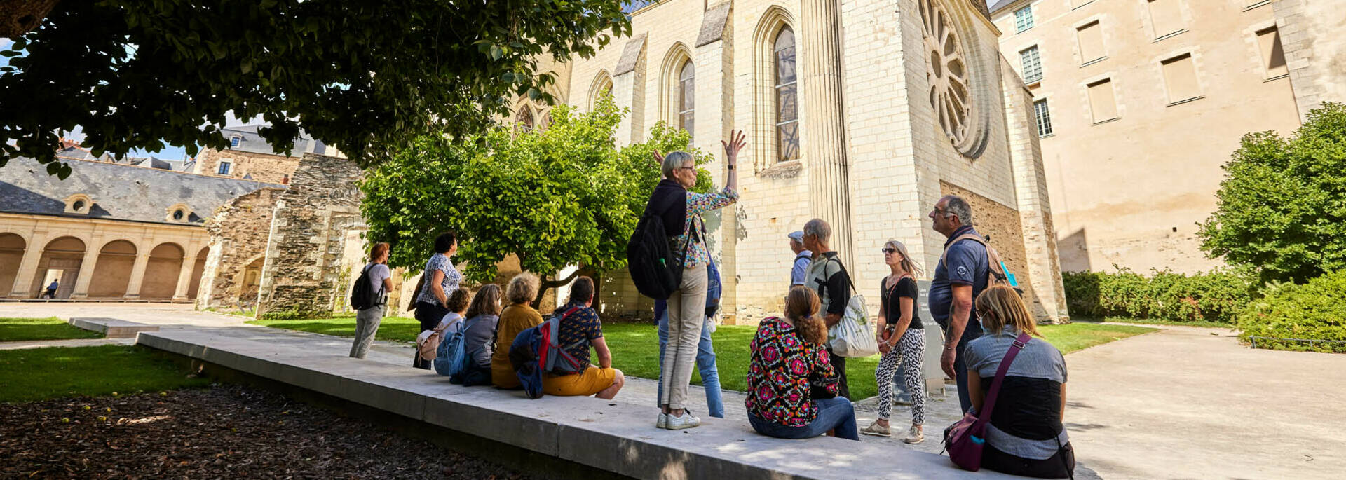 Guide debout sur le muret face à un groupe et à la Galerie David d'Angers
