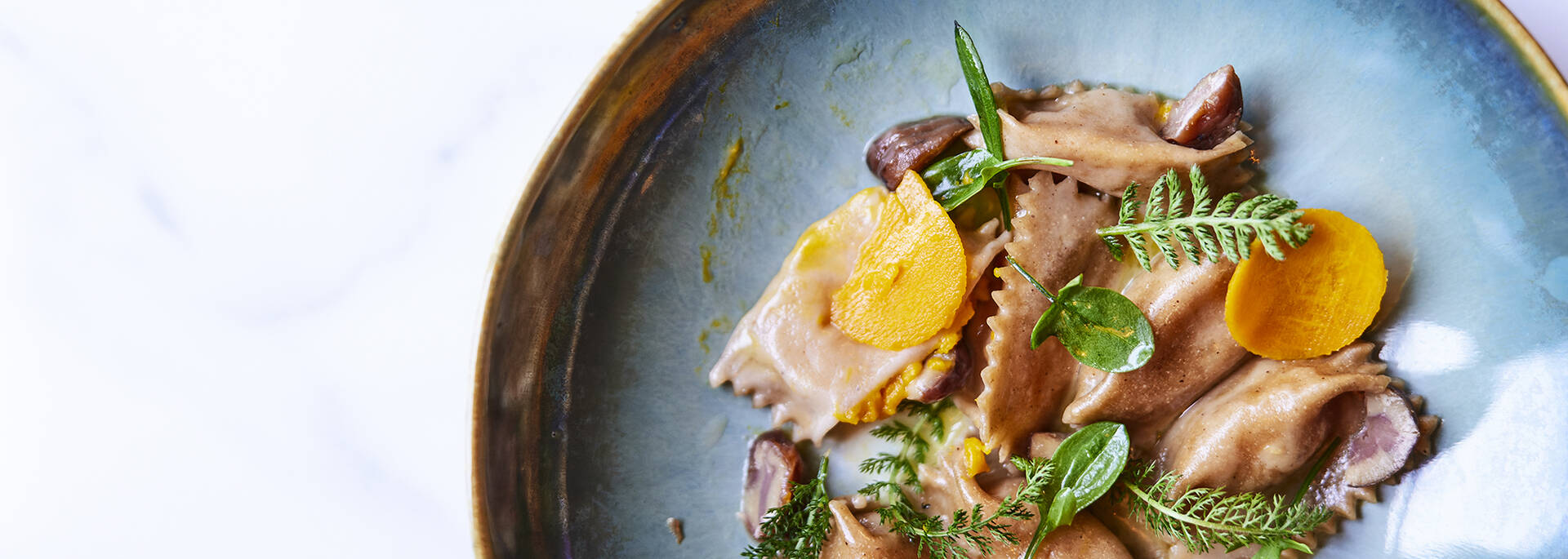 Plan rapproché d'un plat dans une assiette bleu nacré sur une table blanche