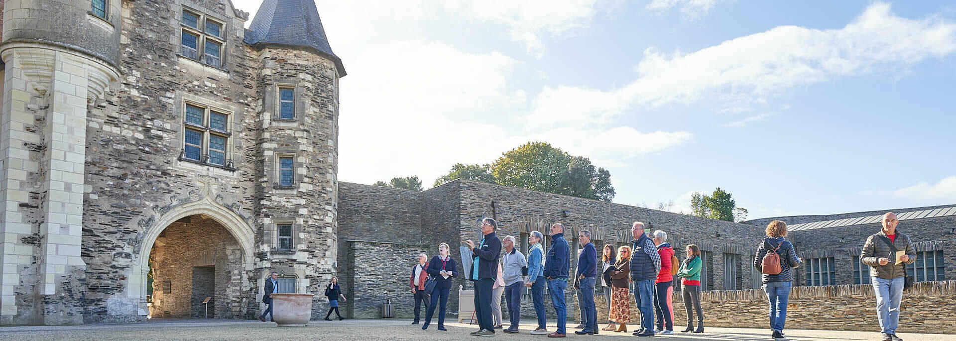 Groupe de visiteurs dans la cour du Château d'Angers face au logis