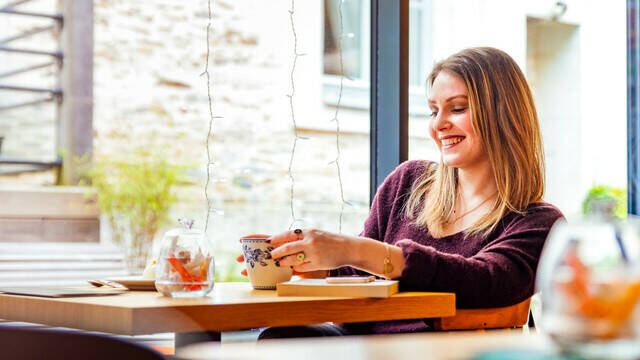 Jeune femme souriante assise à une table dans un salon de thé