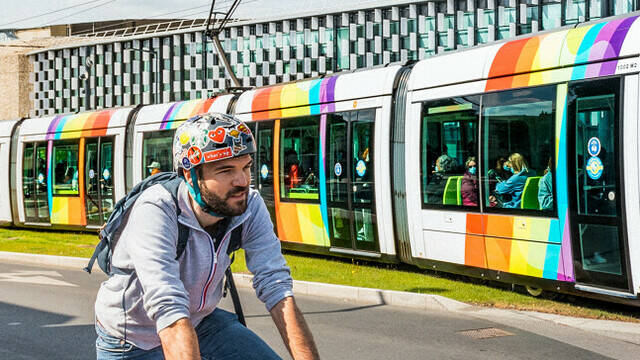 Homme à vélo avec le tram passant derrière, devant le Centre de Congrès d'Angers