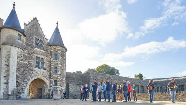 Groupe de visiteurs dans la cour du Château d'Angers face au logis