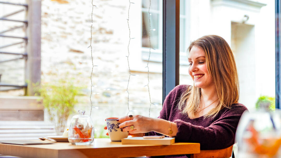 Jeune femme souriante assise à une table dans un salon de thé