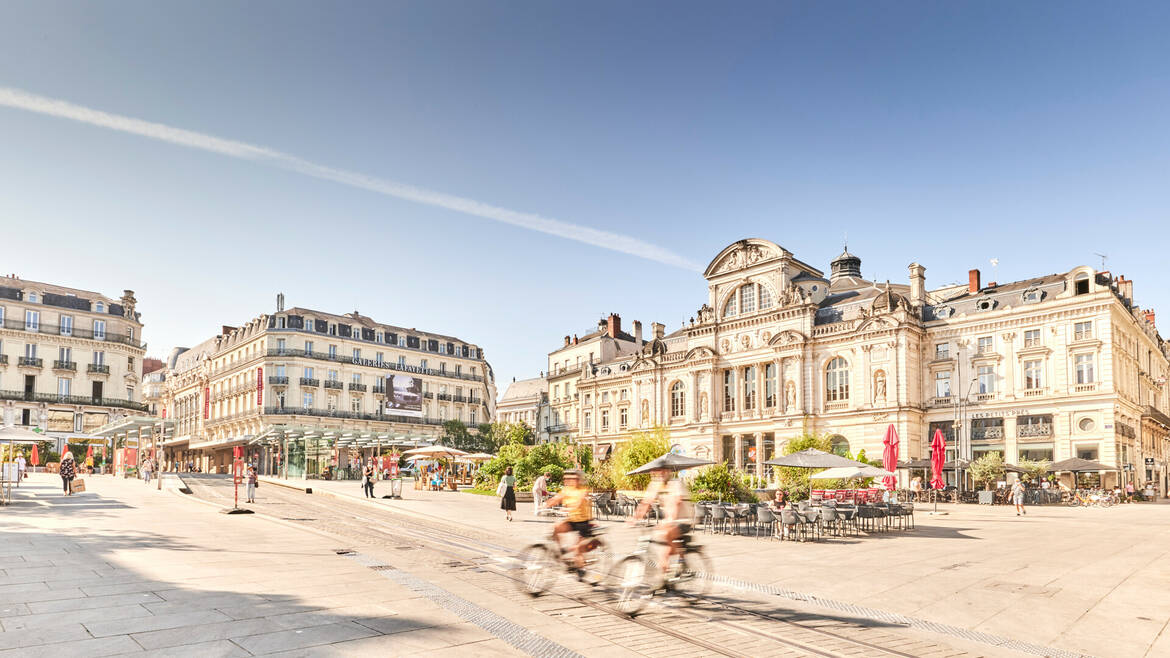 Two cyclists passing Place du Ralliement in front of the Grand Théâtre