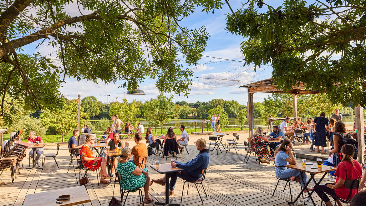 Wide shot of the well-frequented terrace of the Riverside caféin summer on the banks of the Maine