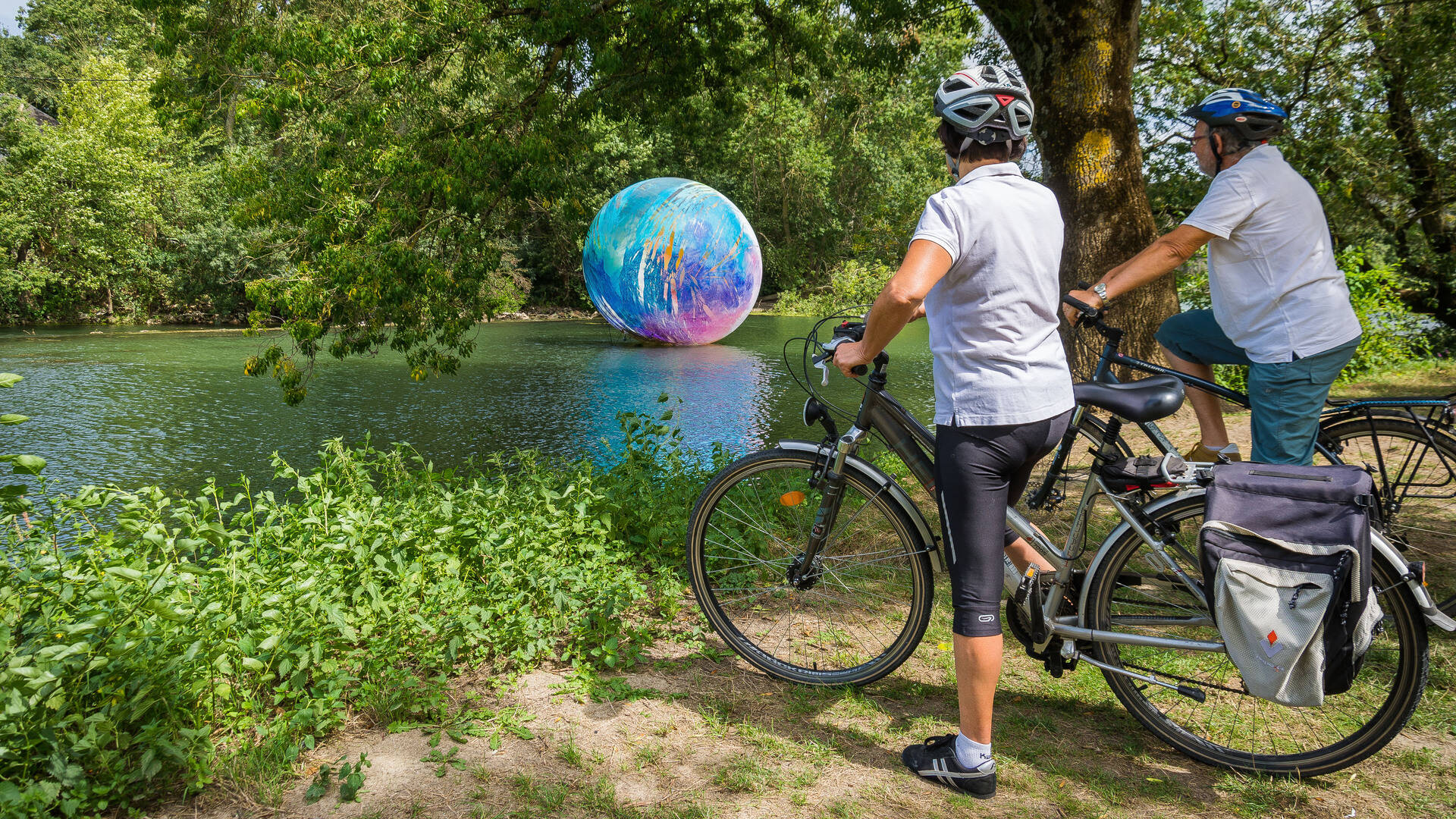 Cycliste devant la boule multicolore posée sur la rivière