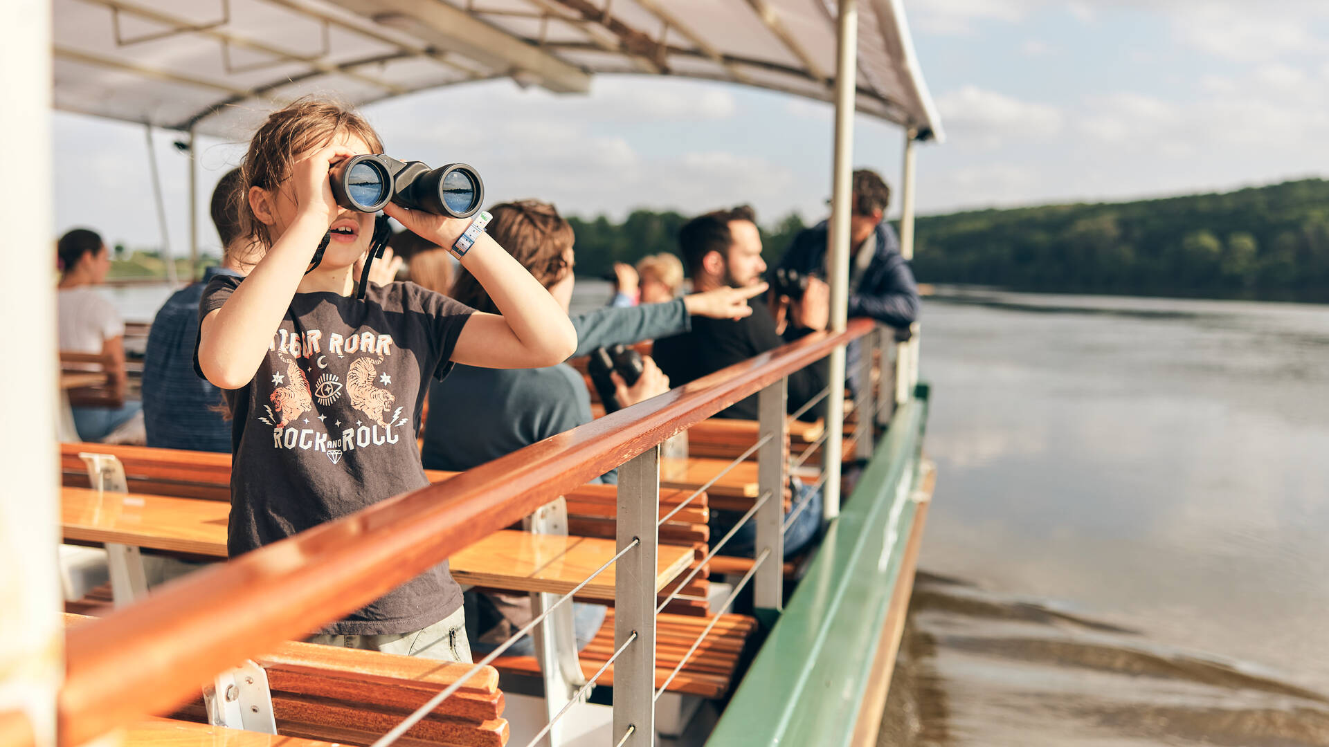 Young girl watching with binoculars on board a boat carrying several people Paddle and canoeing on the Sarthe two people on paddles in the middle of the river, one person in a kayak beside them