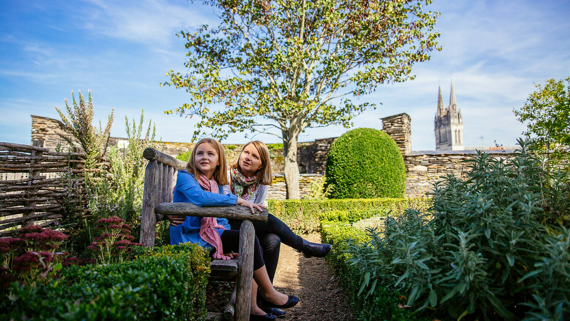 A mother and daughter sitting on a bench in the vegetable garden