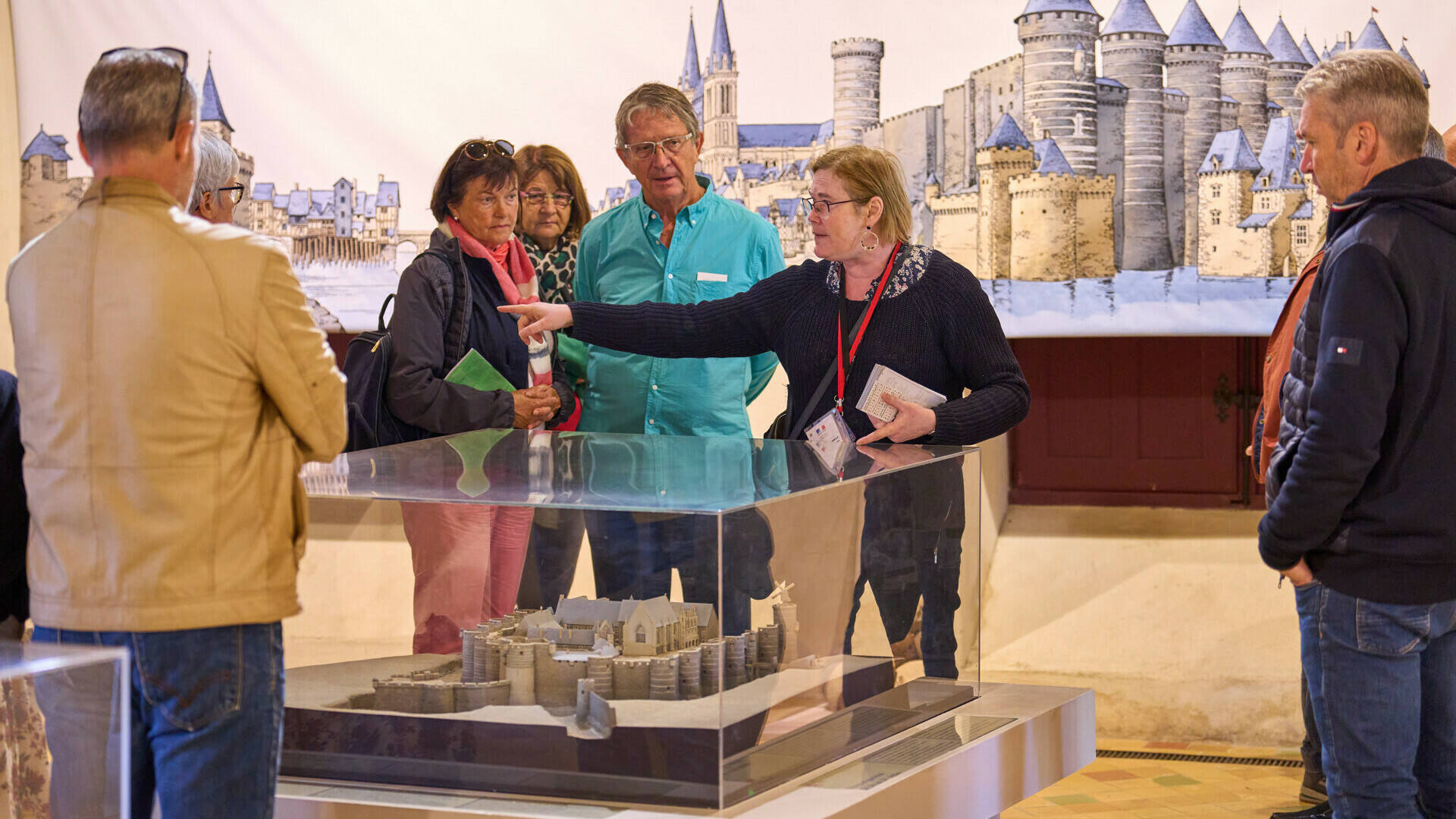 Medium shot of the guide in front of a model of the Château. Guide speaker during a group tour